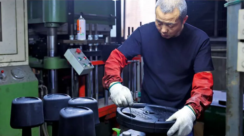 Rubber weight plate being inspected at the moulding press in the IRONHUE factory